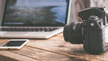 black dslr camera on beige wooden surface