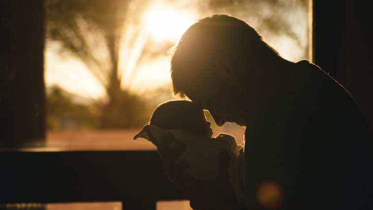 man carrying baby drawing their foreheads